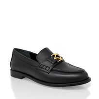 Vista en ángulo de los mocasines color negro con herraje dorado y perfil clásico