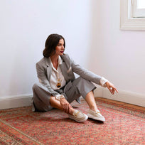 Modelo sentada junto a ventana usando mocasines beige con suela blanca elevada