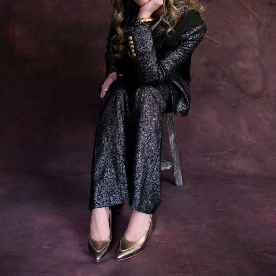 Mujer usando zapatillas de piel metalizada multimetal Fiume de Regina Romero con outfit formal.