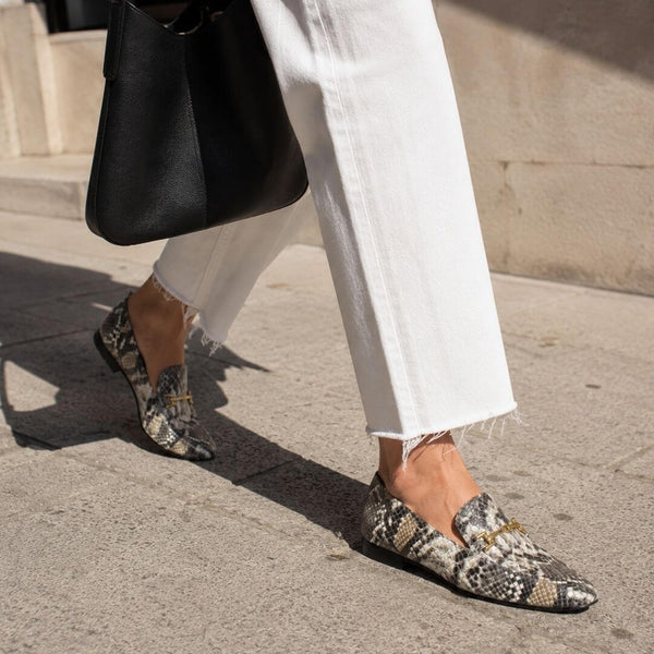 Modelo con gabardina sentada luciendo mocasines con animal print y suela baja