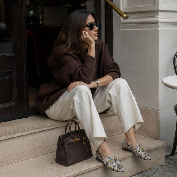 Mujer sentada en interior usando mocasines con animal print en look casual claro