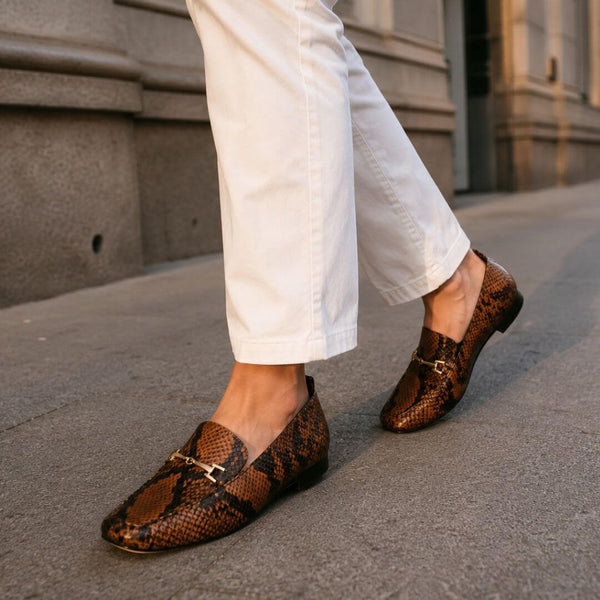 Modelo sentada luciendo mocasines con animal print en tonos cálidos en interior