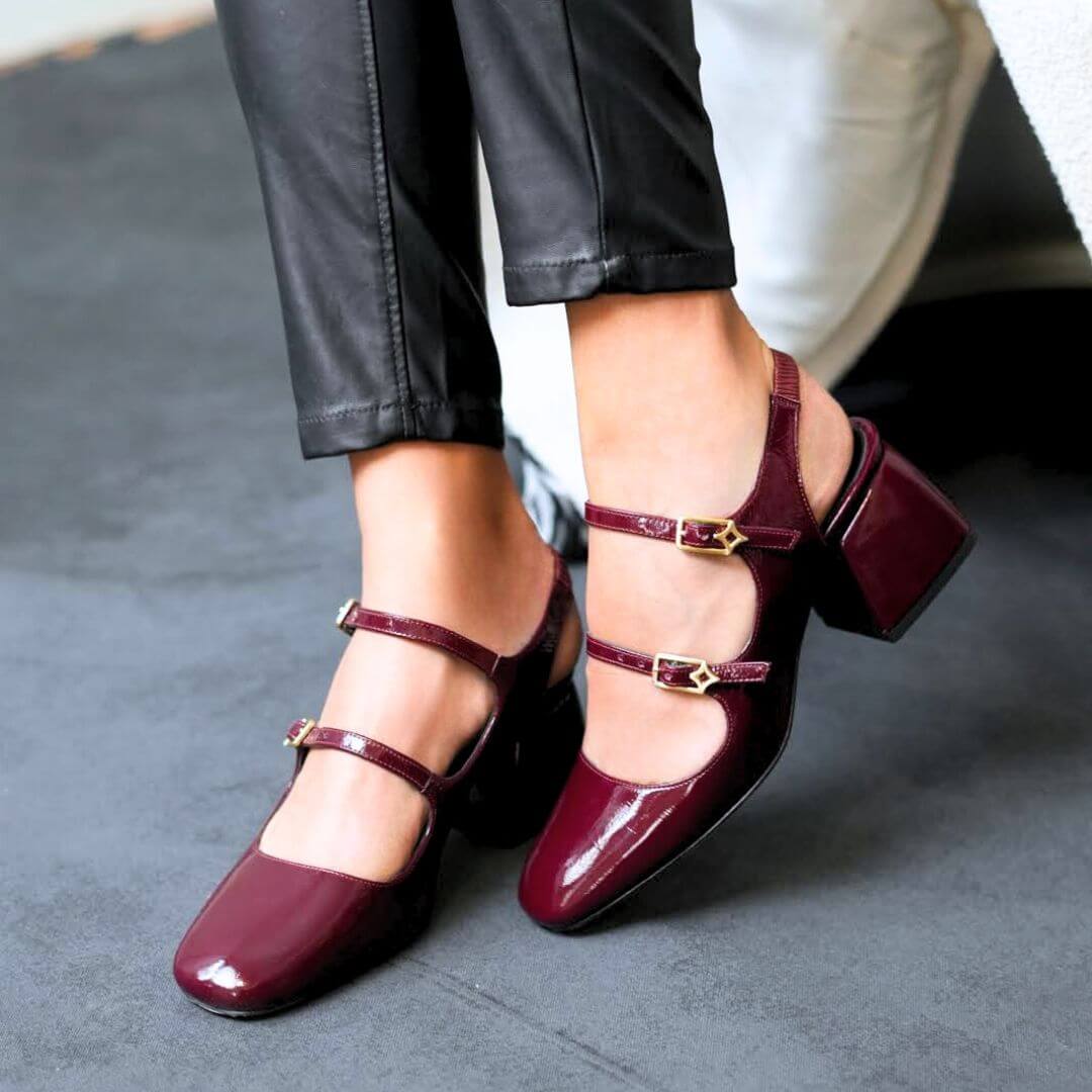 Mujer usando zapatillas de charol vino modelo Alessia de Regina Romero combinadas con pantalón negro elegante