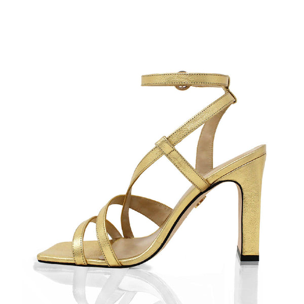 Vista lateral opuesta de sandalias de piel color oro con tiras cruzadas, modelo Pia de Regina Romero